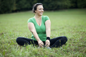 Cheerful plus sized woman stretching in the park.Emotional eating